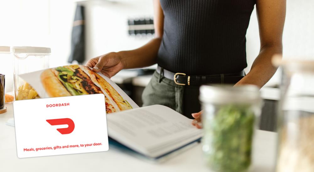 woman flipping through magazine with DoorDash gift card.